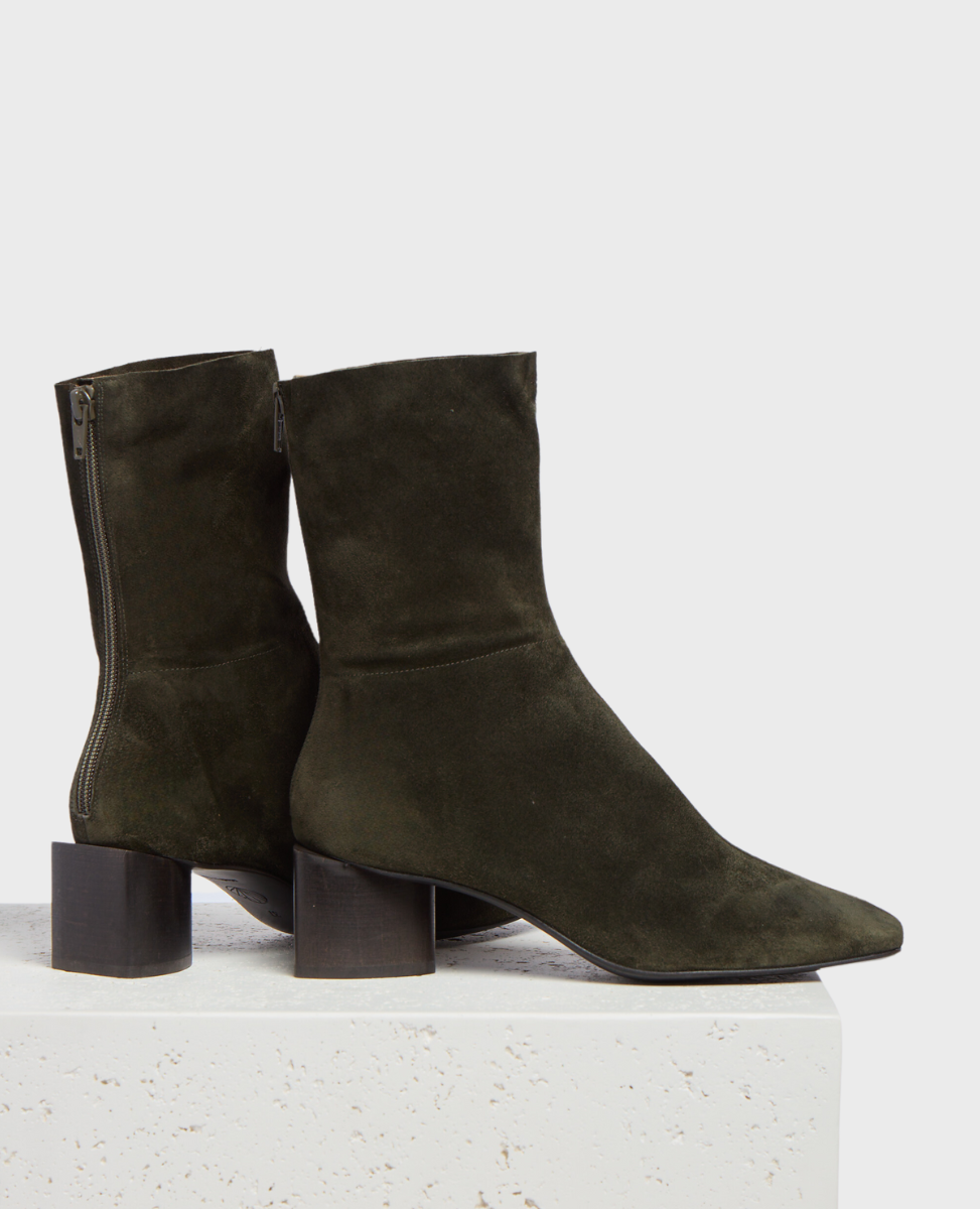 A pair of dark olive green suede ankle boots with a pointed toe, side zipper, and a chunky, low block heel.
