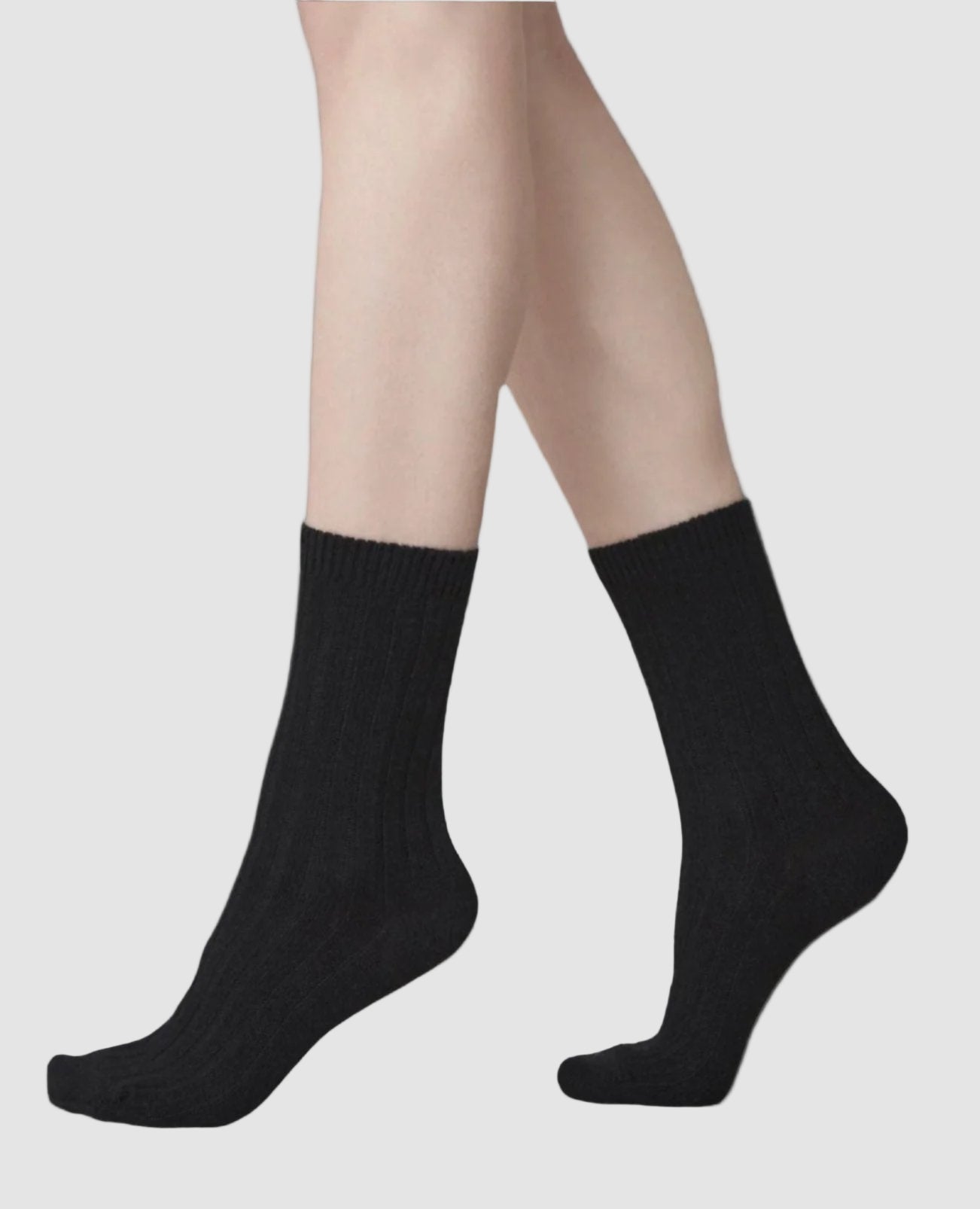 Swedish Stockings Bodil wool socks shown worn on a woman's foot from the knee down while she stands on her toes.