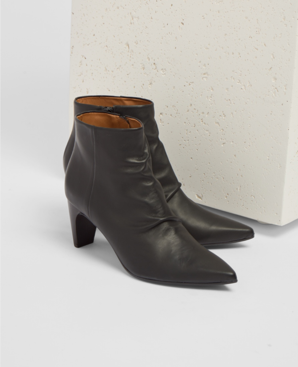 Pair of black leather ankle boots on a light gray background