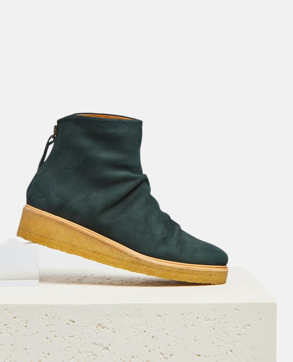 Green ankle boot with brown sole on a white platform