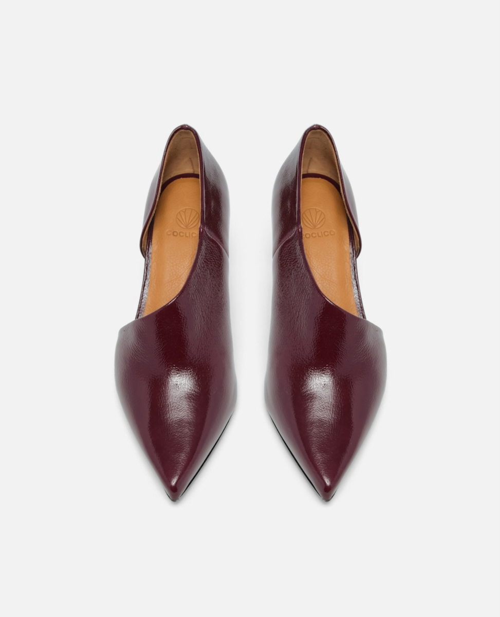Pair of maroon pointed-toe shoes on a light gray background