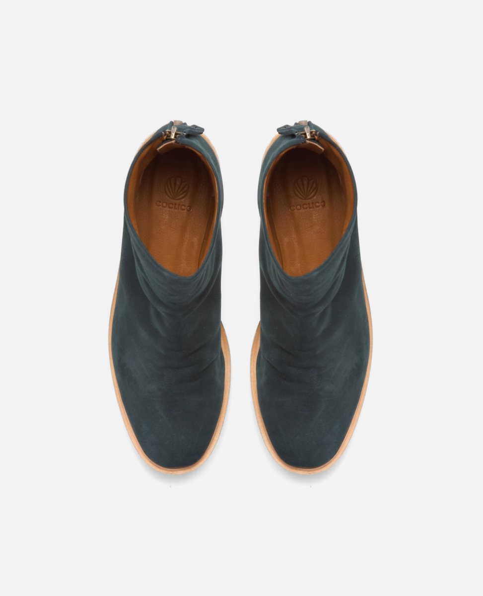Pair of teal ankle boots with brown soles on a light gray background