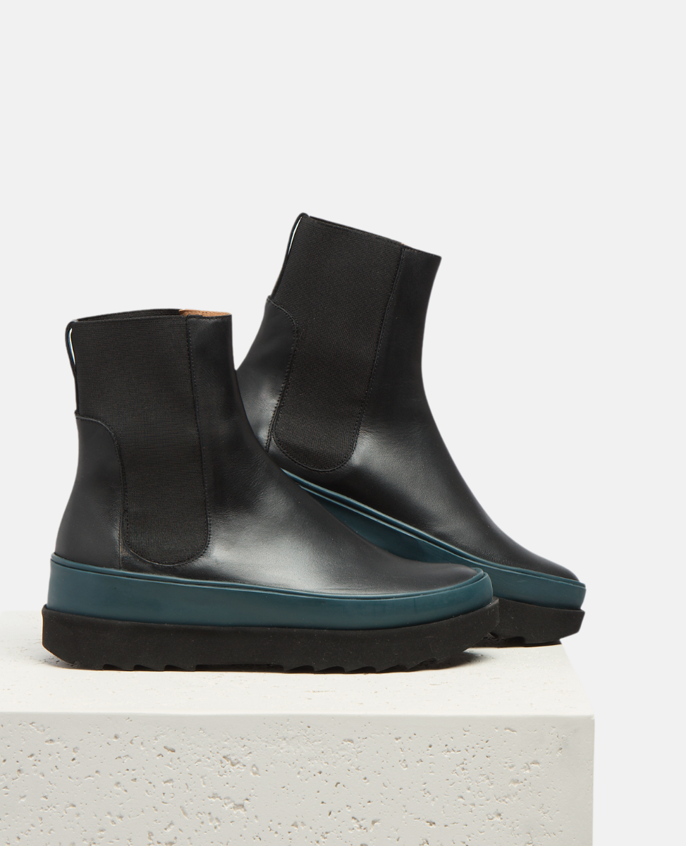 Black ankle boots with blue soles on a white background