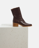 Brown leather boot on a light gray surface with a white background 4