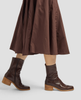 Brown leather boots worn with a matching brown skirt on a white background 5