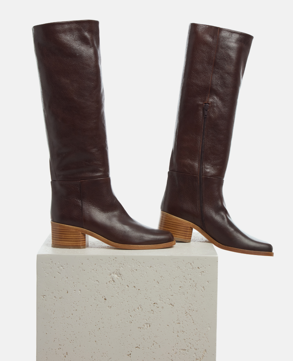 Pair of brown knee-high boots on a light gray background