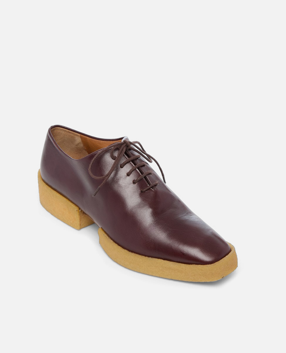 Brown leather shoe with a wooden sole on a white background