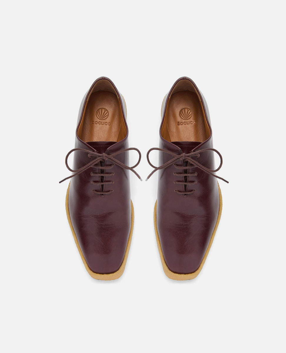 Pair of brown leather shoes with tan soles on a white background