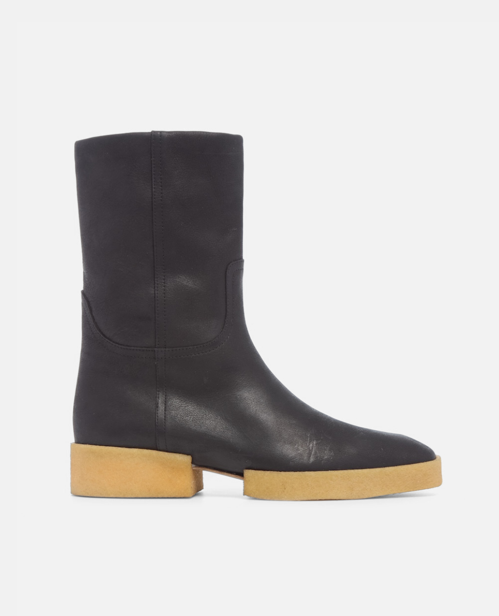 Black leather boot with a tan sole on a white background