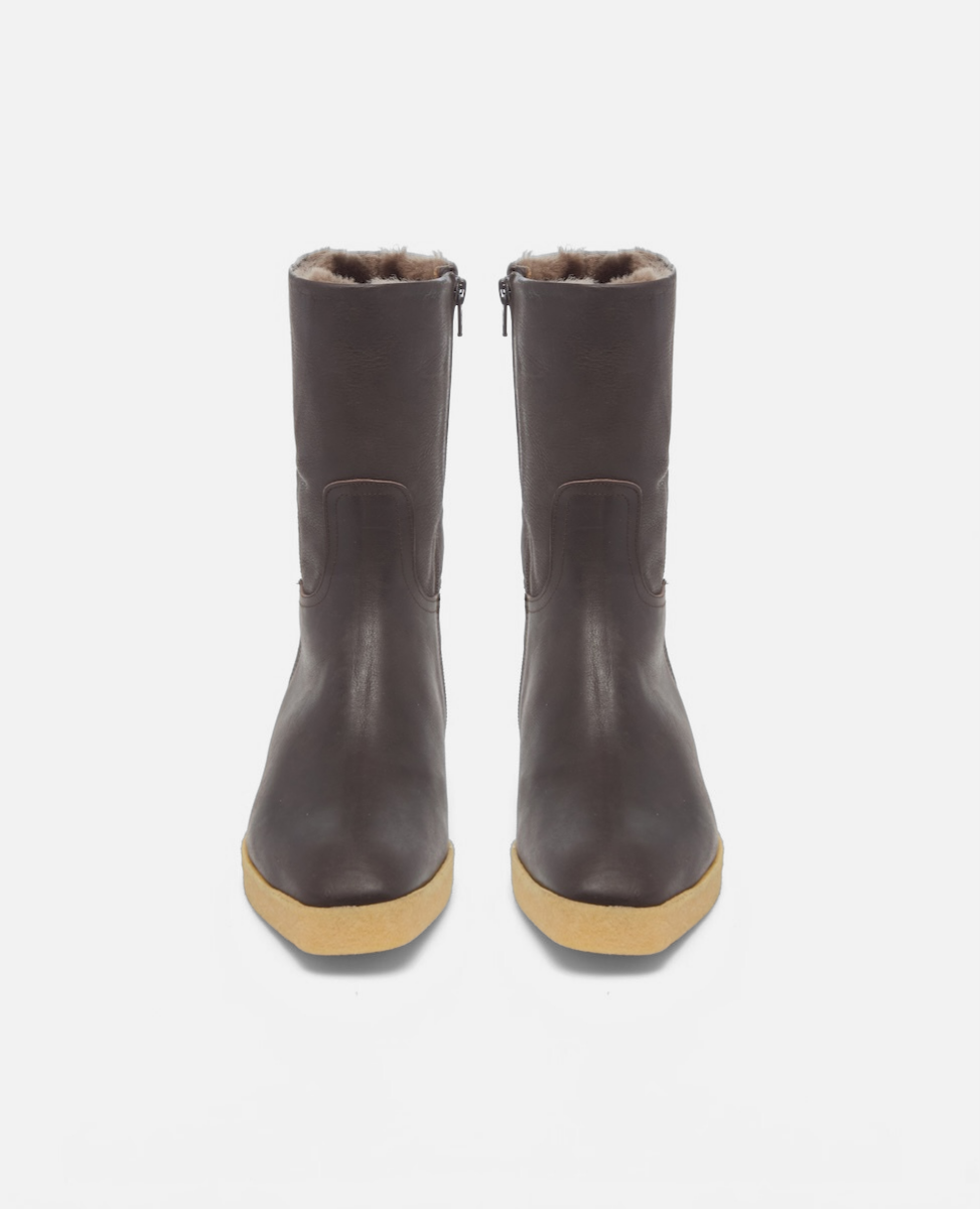 Pair of brown leather boots with beige soles on a white background