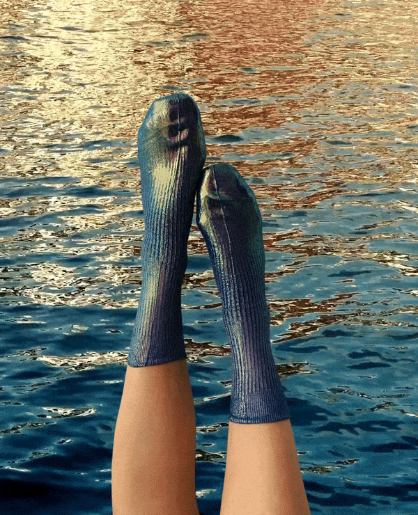 GIF of feet up in the air wearing metallic socks, water moving in the background