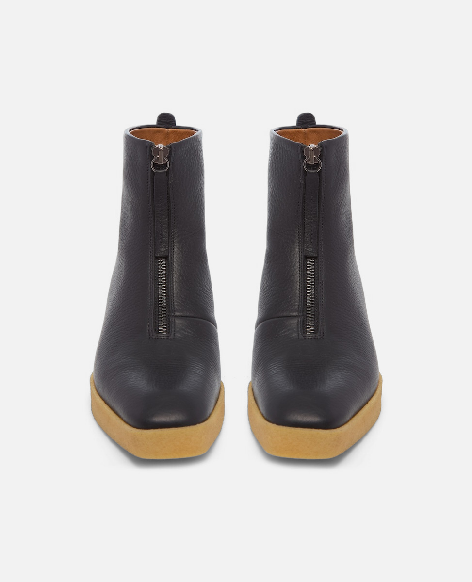 Pair of black ankle boots with brown soles on a white background