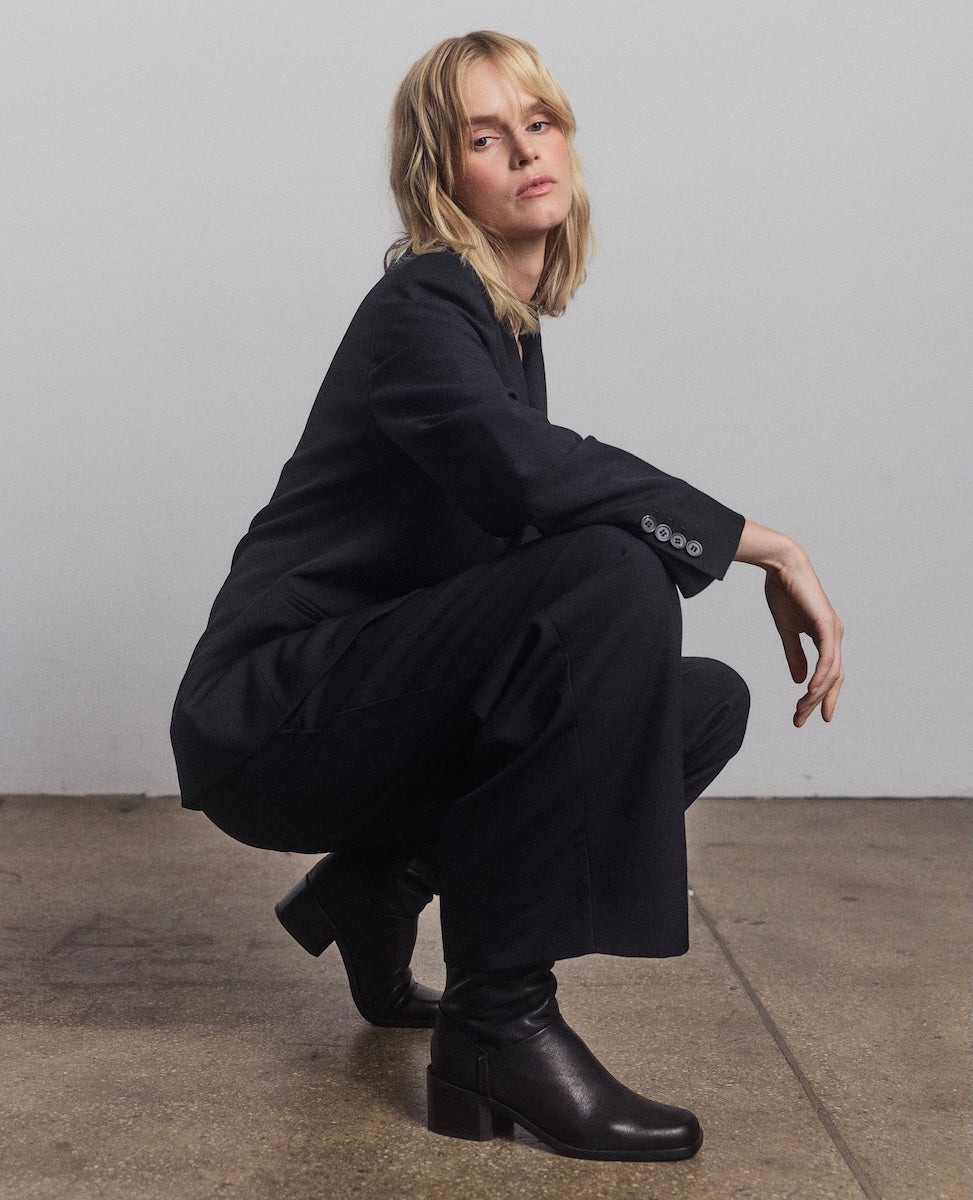 Person wearing a black outfit squatting on a plain background