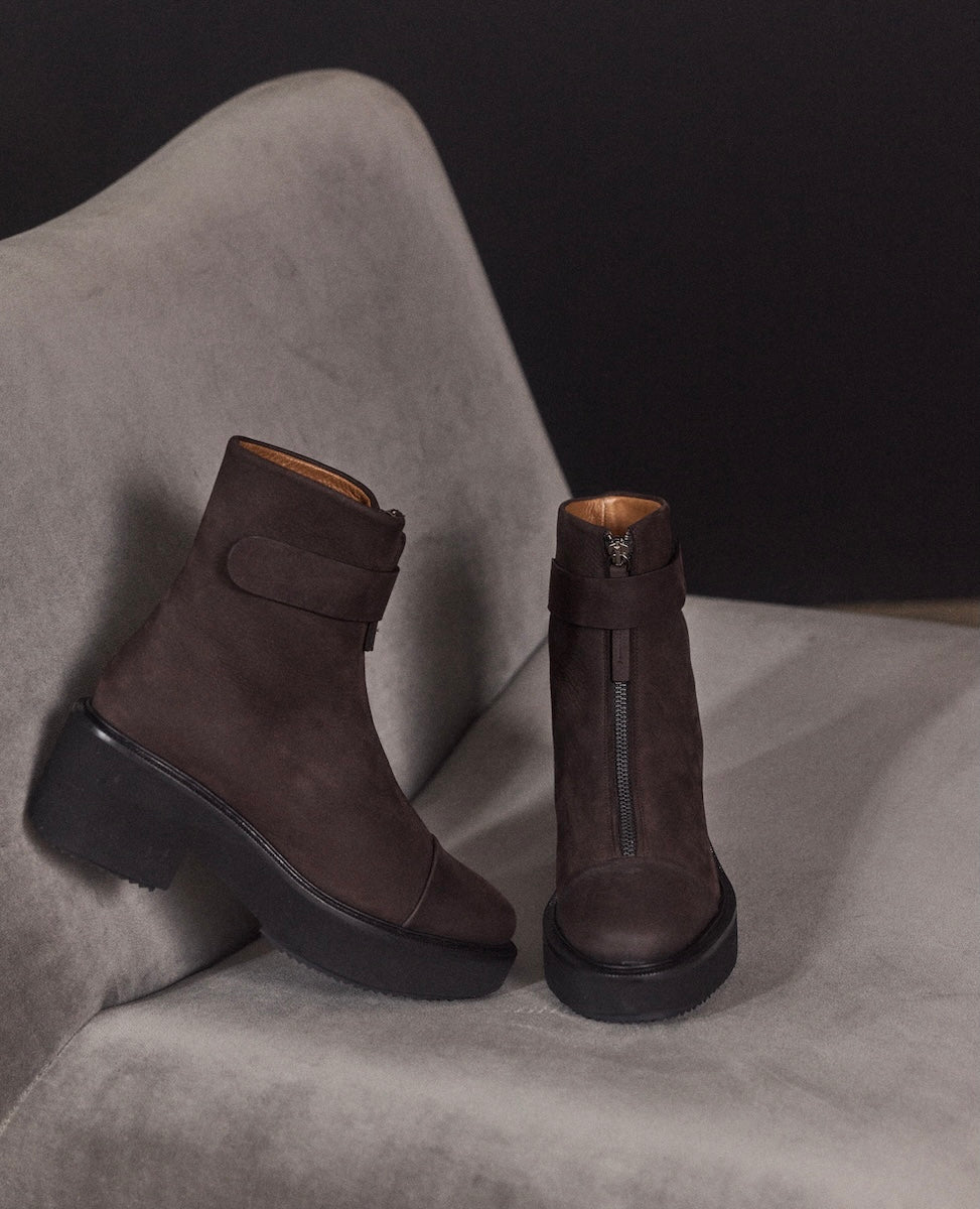 Pair of brown suede boots on a gray surface with a dark background