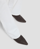 Black pointed-toe shoes worn with white pants on a light gray background 6