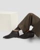 Person wearing black shoes and brown pants sitting on a white surface with a textured white cushion. 5