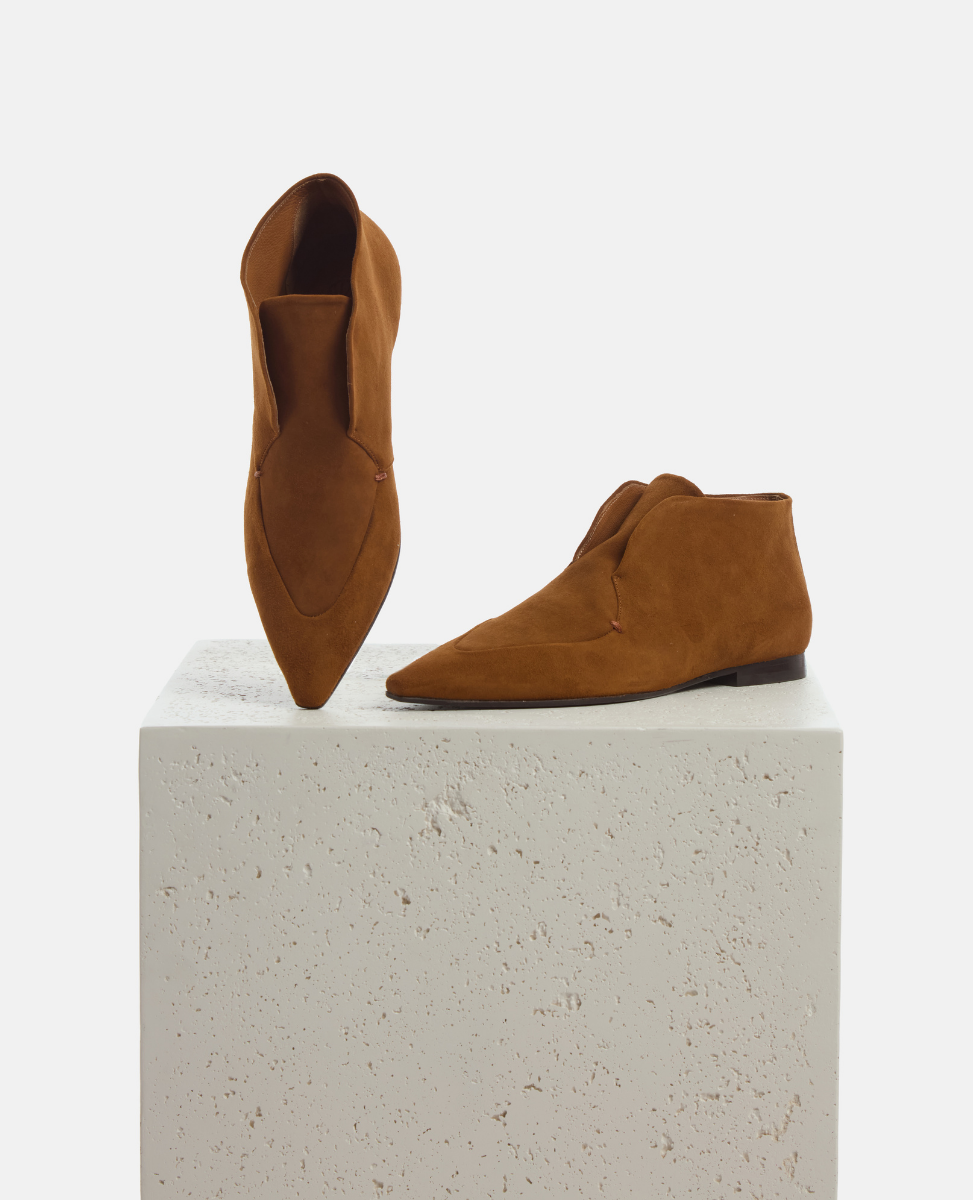 Pair of brown suede shoes on a white pedestal with a white background