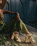 Woman sitting down in a garden wearing a green jumpsuit and the April Heel in Latte Machiatto.  5