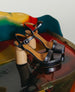 Angel Platform Sandal in Black Pearl Patent placed on a colorful table. 4