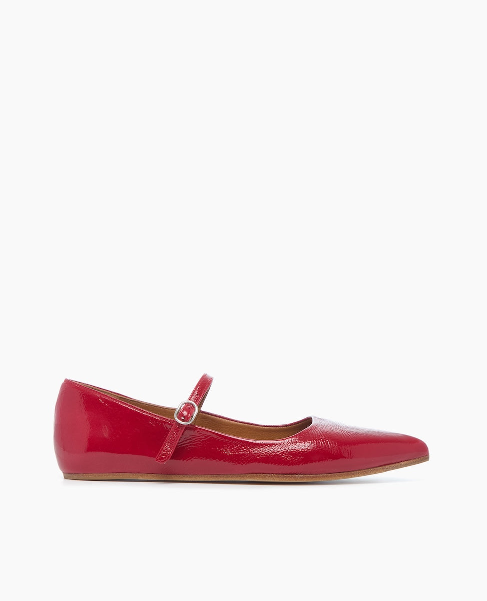 A glossy red Mary Jane flat shoe with a rounded toe, a thin strap featuring a small buckle, and a smooth, shiny texture.