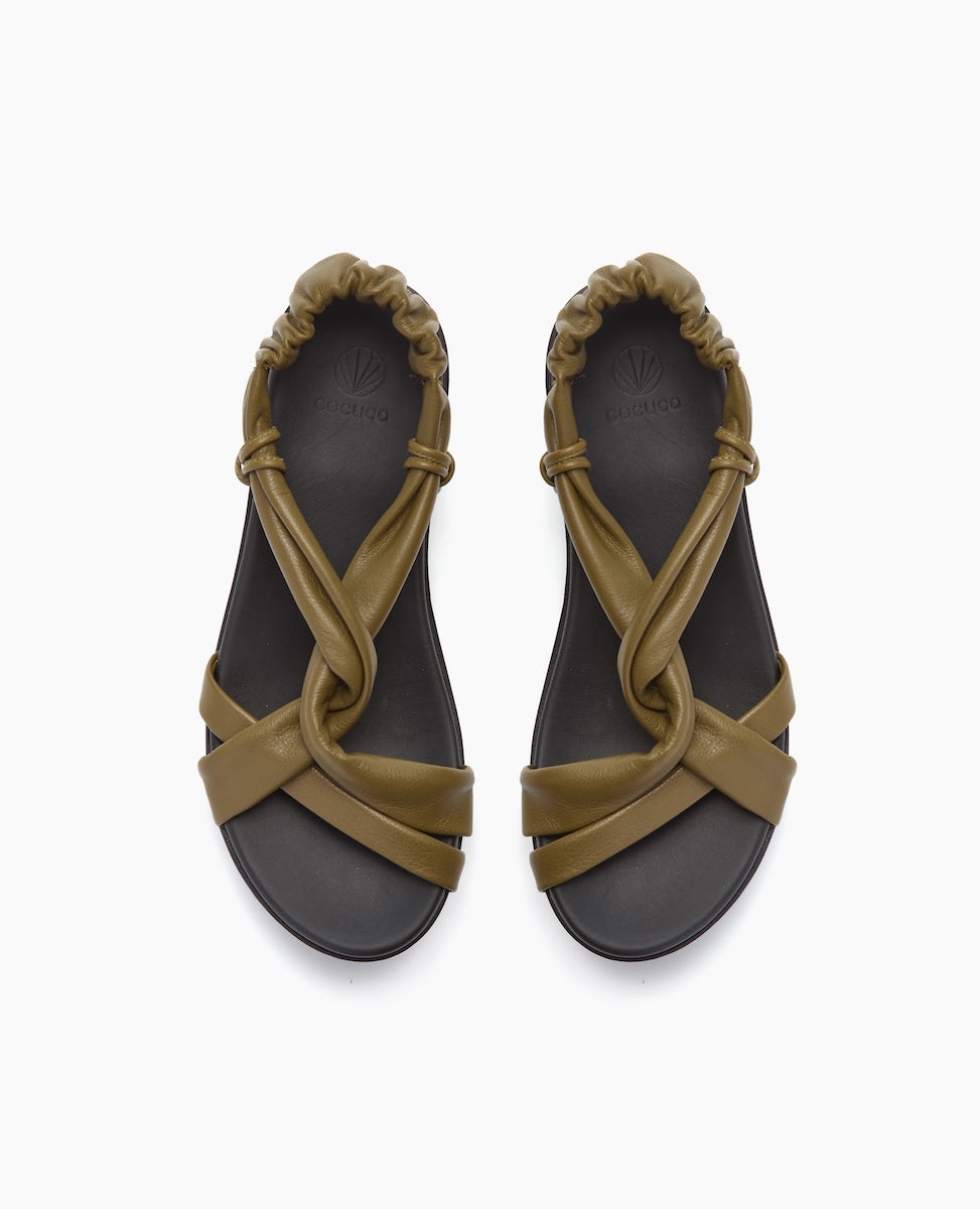 A pair of olive green sandals featuring a crisscross strap design, cushioned footbed, and elasticized back strap, made from smooth, matte leather-like material.
