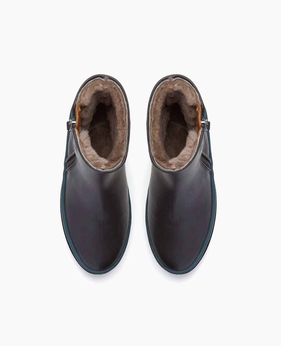 A pair of sleek, black ankle boots with a smooth leather exterior, featuring a plush, brown fur lining visible at the top, and a subtle buckle detail on the side.