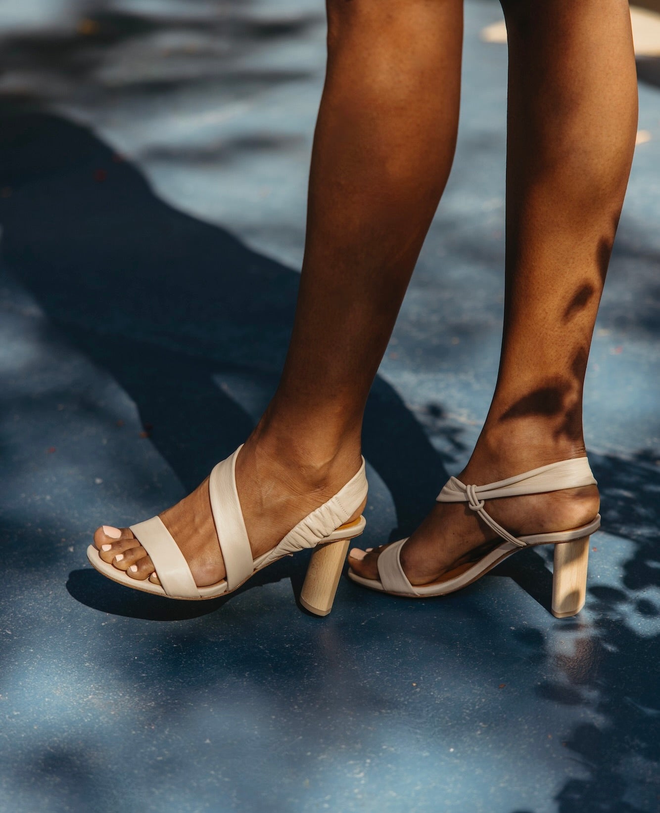 Side view of legs and feet of a woman standing and wearing the Gabby Heel in Latte Macchiato.