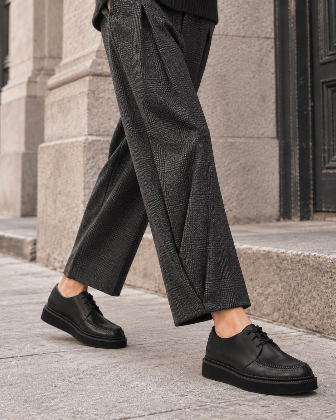 The Coclico Gali Creeper shoes on a model wearing black pants and walking in a city