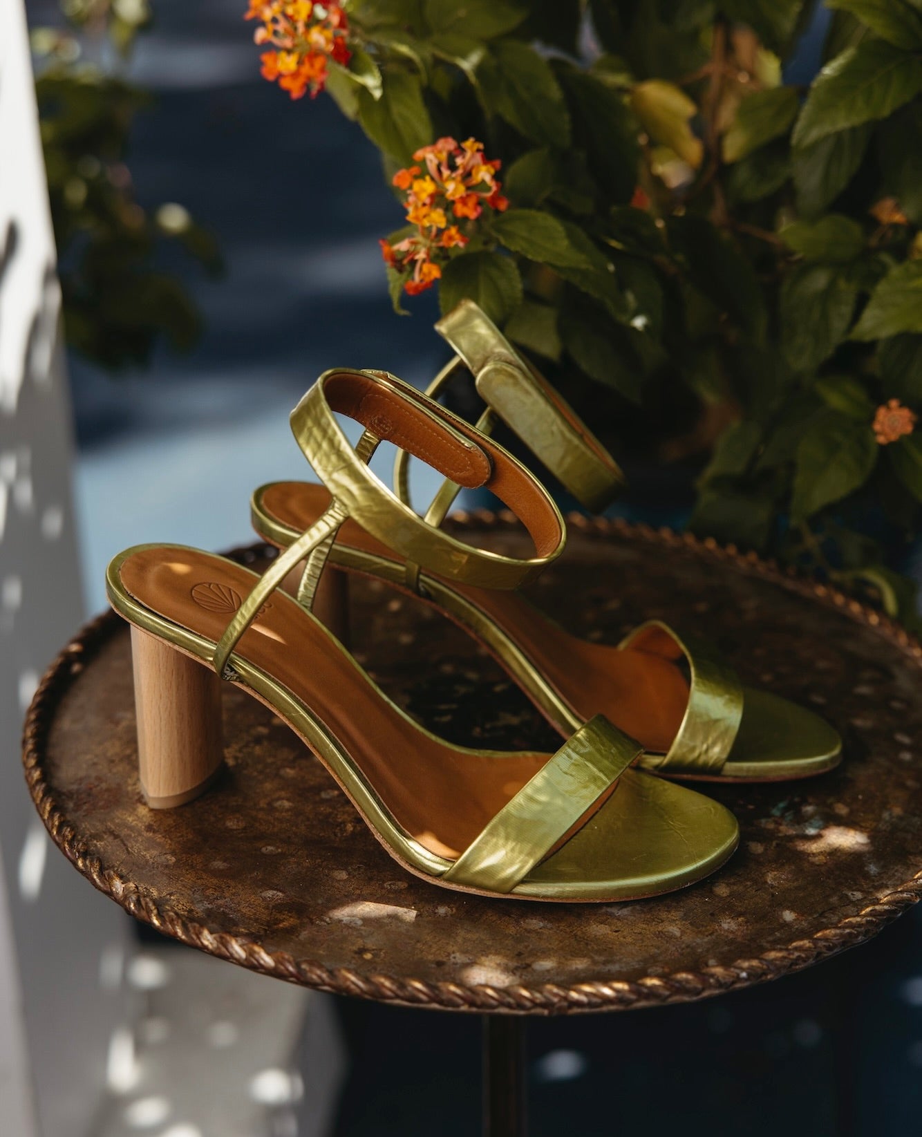 Side view of a pair of the Gina Heel in Chartreause Antiqued Patent on a gilded plate.