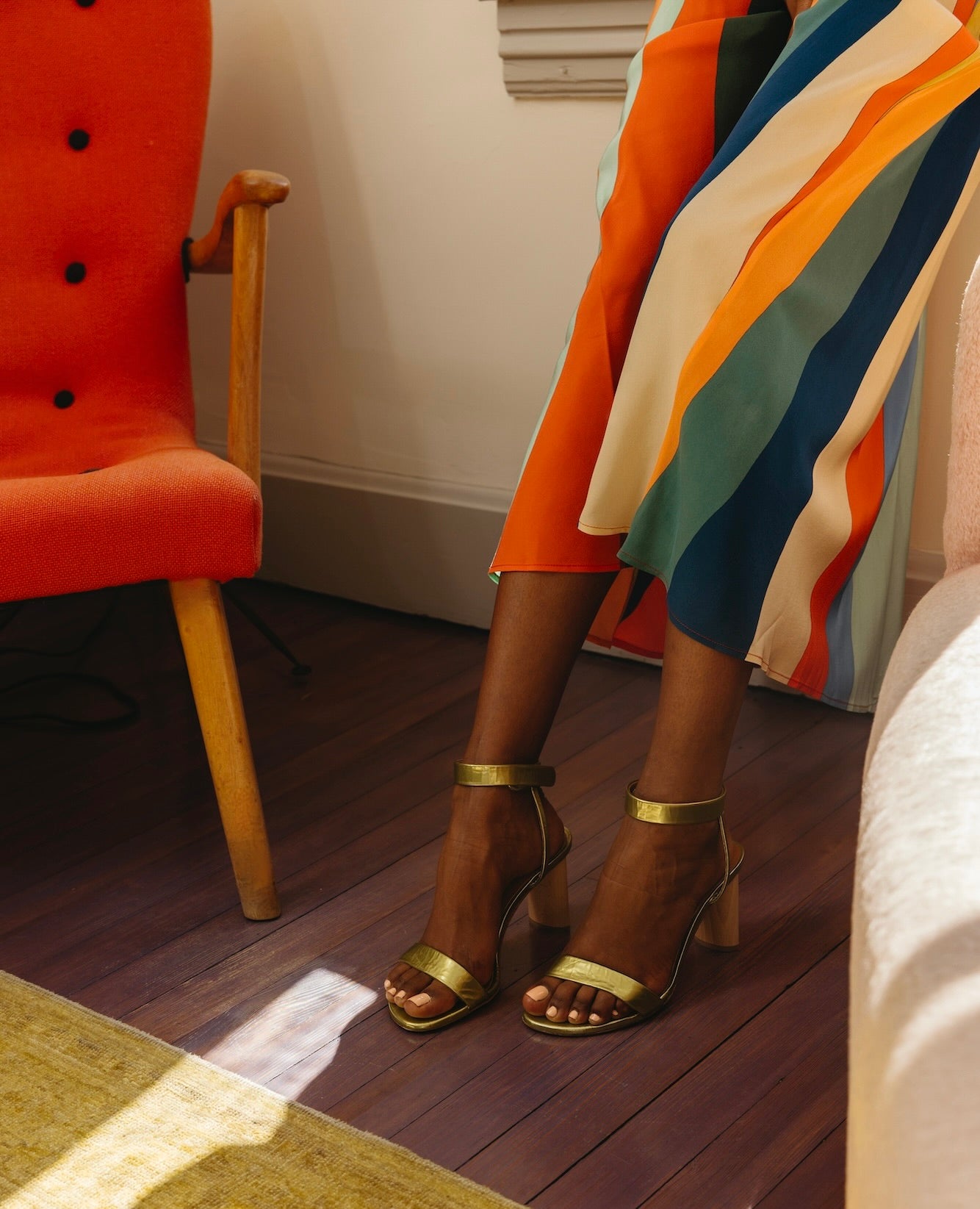 Front view of the legs of a woman draped in a rainbow skirt wearing the Gina Heel in Chartreuse Patent.