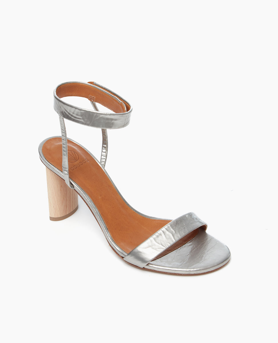 Angled view of the Gina Heel in Chateau Grey featuring a straight, narrow front strap and ankle strap that is secured with velcro for a supportive and seamless look as well as an artfully sculpted heel.