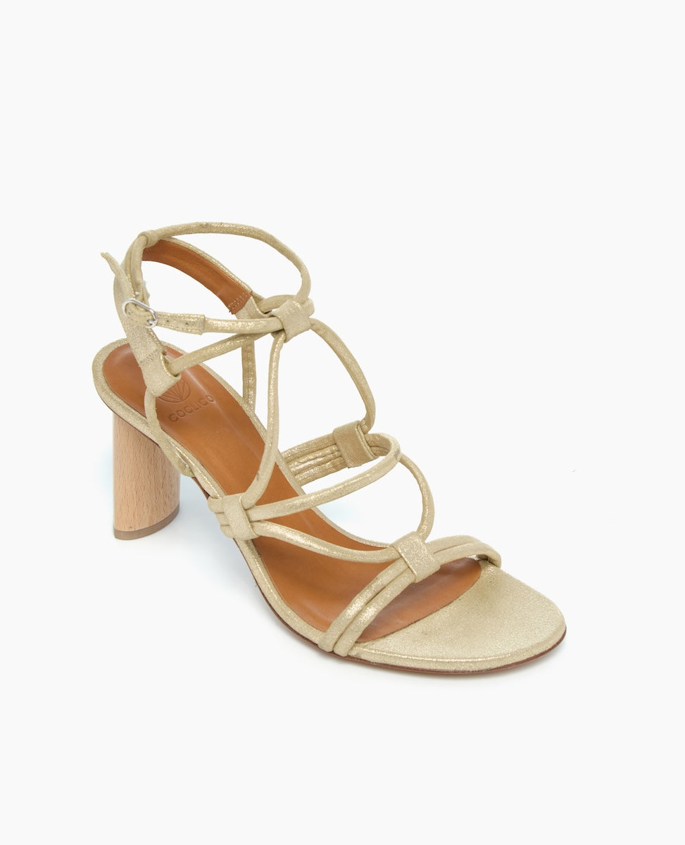 A stylish sandal featuring a metallic gold finish, strappy design, open toe, and a chunky wooden block heel.