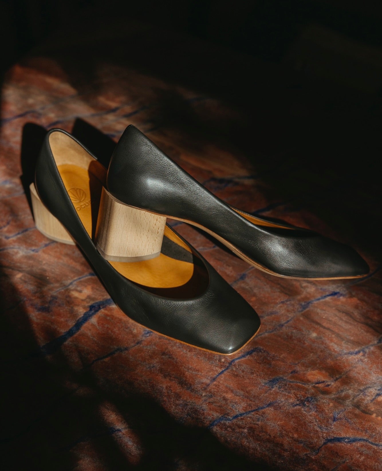Side angled view of the Icy Pump in Black Leather against a marble floor.