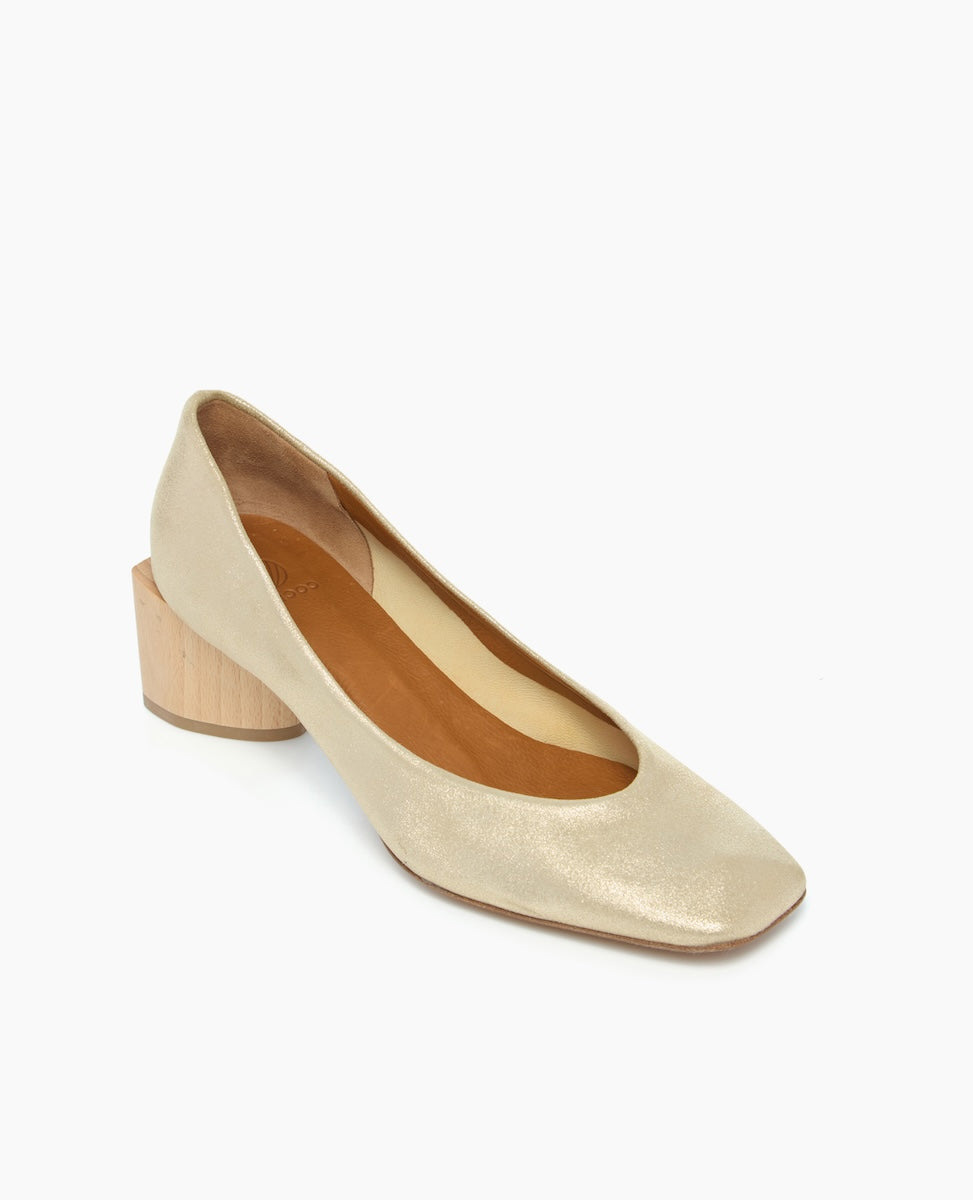 A sleek, beige leather shoe with a rounded toe, featuring a low, chunky wooden heel and a smooth, polished texture.