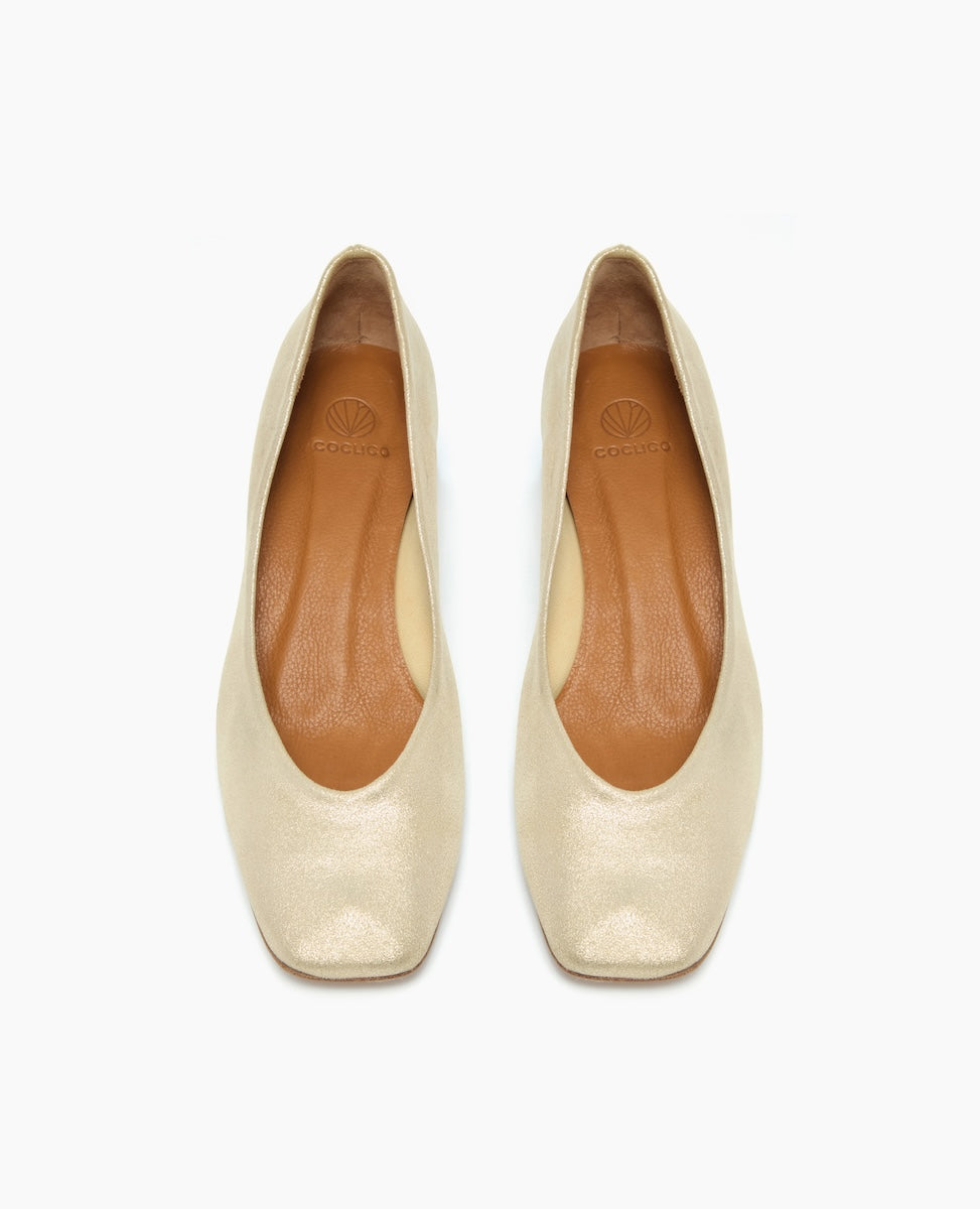 Elegant, cream-colored leather flats with a smooth texture, featuring a square toe design and a subtle logo embossed on the tan insole.