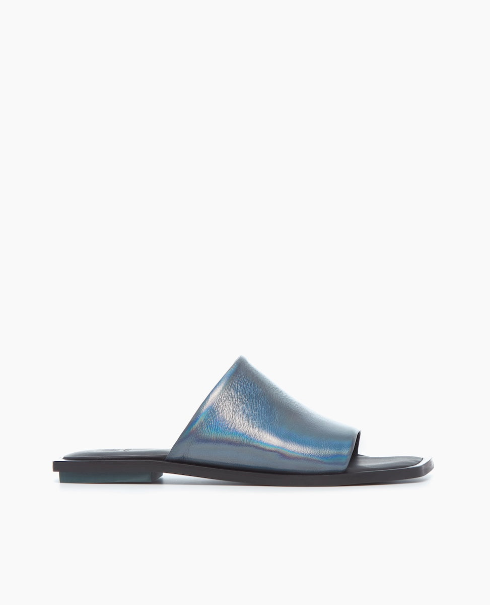A sleek, iridescent blue slide sandal with a smooth, glossy leather upper, featuring a flat black sole and an open toe design.