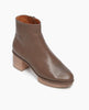 Angled view view of the Coclico Nigella Clog in Taupe Leather. Set on a solid wood heel and platform, the midsole is rounded and completely unique, with a simple, clean bootie silhoute. Side tab. Inside-zip closure. 2