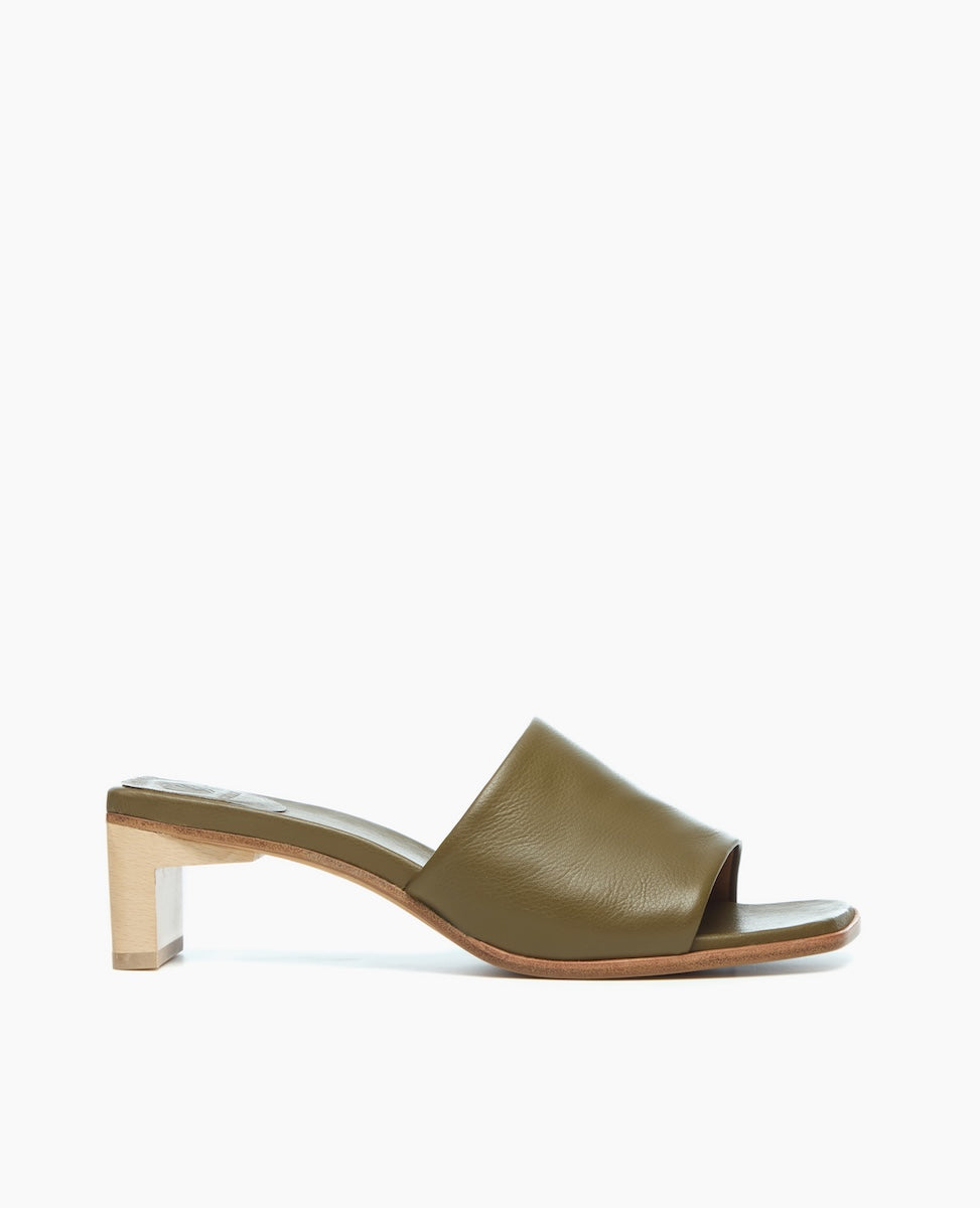 A sleek, olive green leather slide sandal with a wide strap, open toe, and a low, block wooden heel.