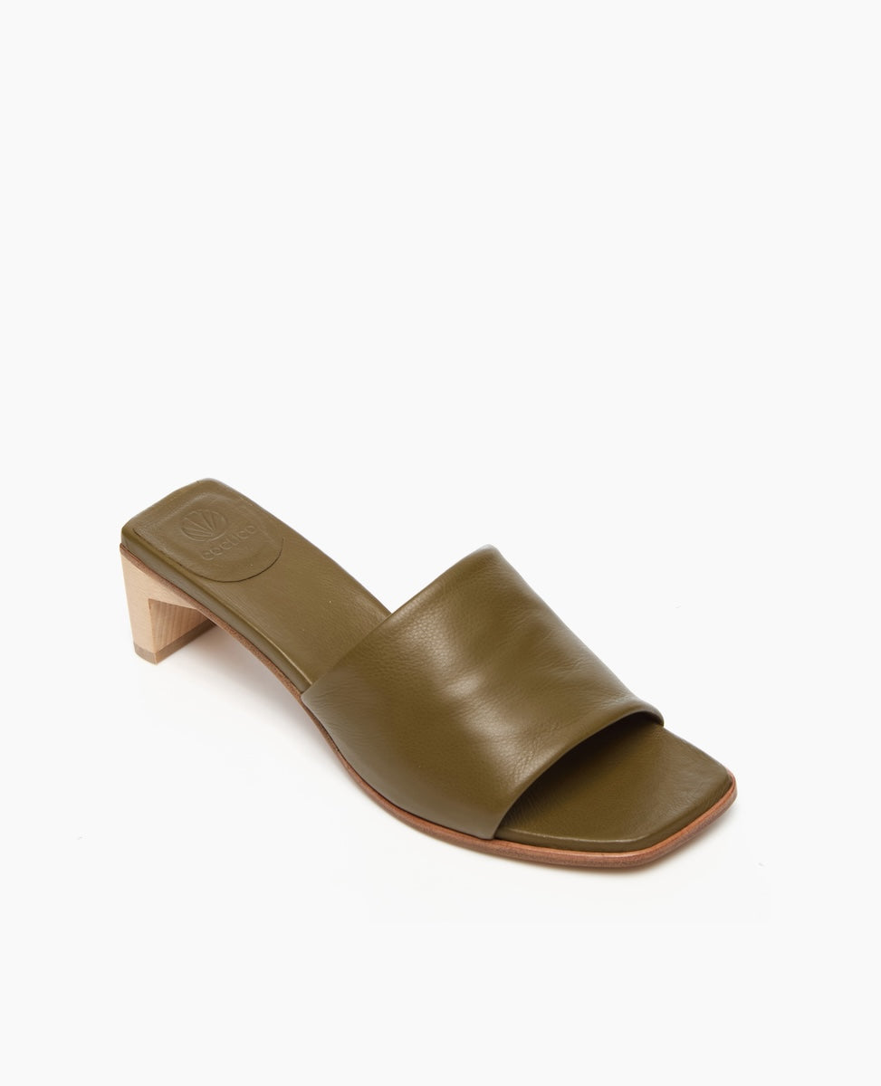 A sleek, olive green leather slide sandal features a wide strap, a square toe, a low wooden block heel, and a smooth finish.