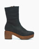 A black leather ankle boot with a smooth texture, featuring a chunky wooden platform heel and a side zipper for closure. 3