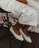 Regal Sneaker in greige on model sitting on a bar stool 10