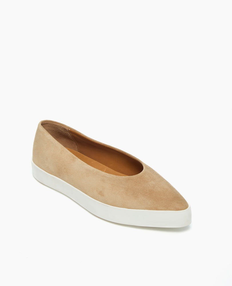 A beige suede slip-on shoe with a pointed toe, a white rubber sole, and a smooth, minimalist design.