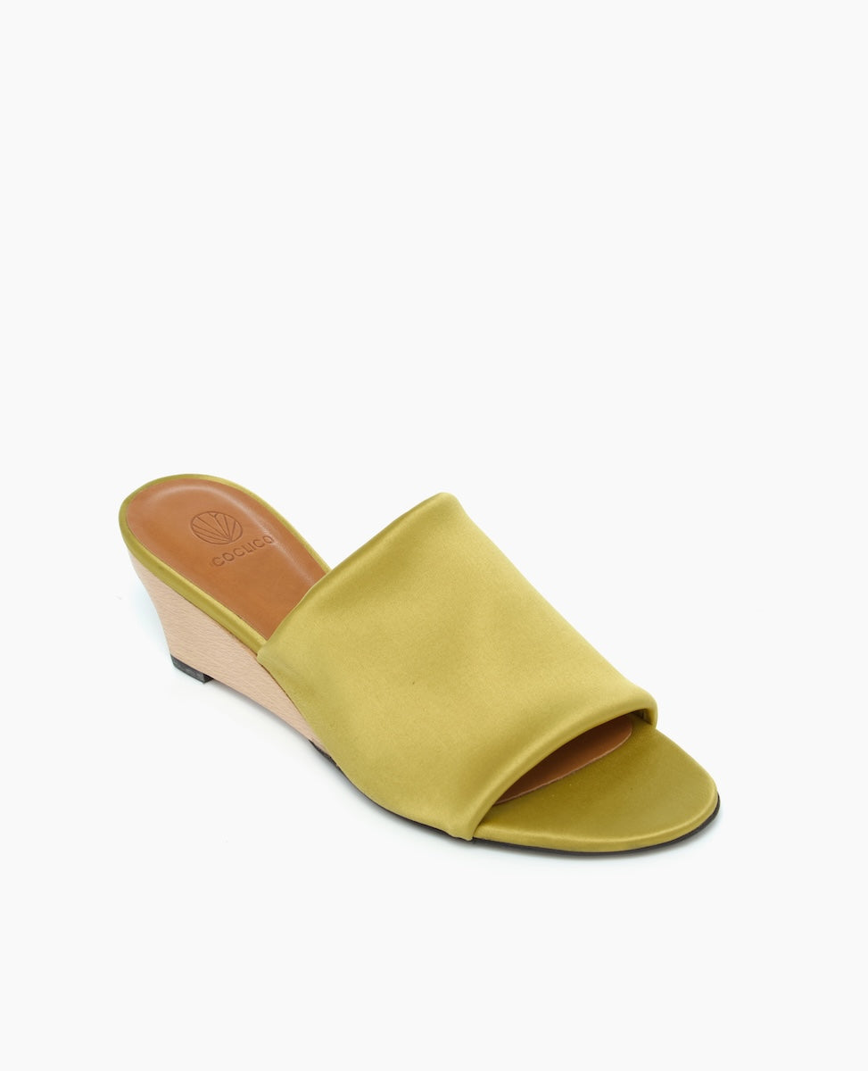 A stylish open-toe wedge sandal featuring a smooth, olive-green fabric upper, a tan wedge heel, and a cushioned brown insole with a subtle logo imprint.