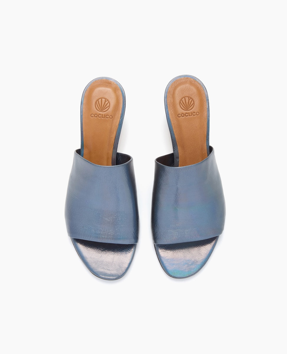 Blue open-toe slides with a smooth, shiny leather upper, tan leather insole featuring a logo, and a simple, sleek design.
