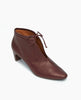 Coclico Waffles Bootie in Merlot Leather; angled view featuring a softly arched solid wood heel and gathered tie at the ankle revealing just enough to be both feminine and practical. 2