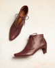 Coclico Booties in Merlot Leather with the left shoe laying on its side. 5