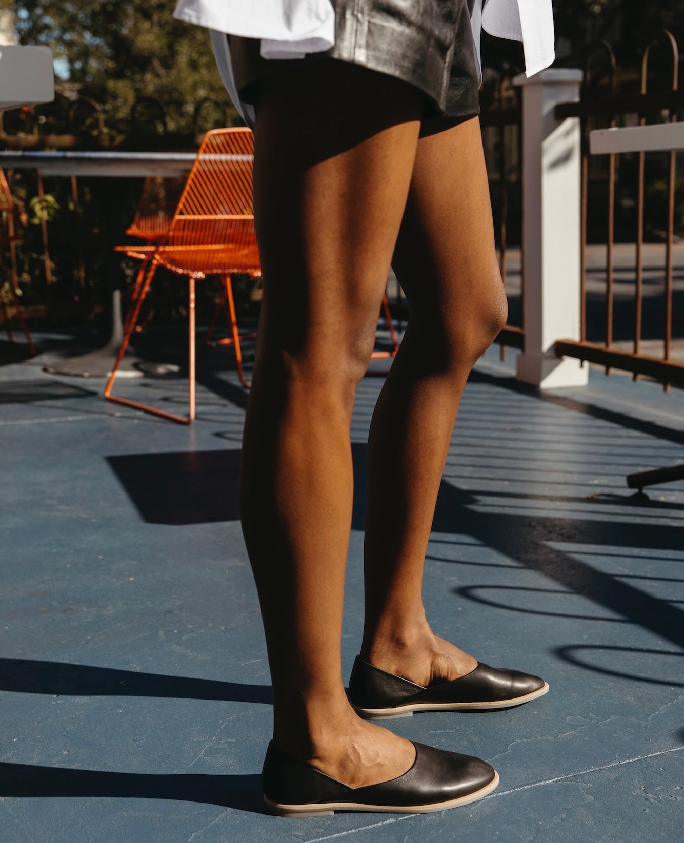 Legs of a woman standing outside wearing the Yen Flat in Black.