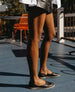 Legs of a woman standing outside wearing the Yen Flat in Black.  5