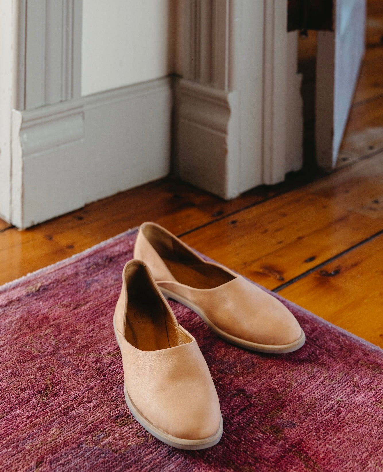 Pair of the Yen Flat in Faun placed on a pink rug.