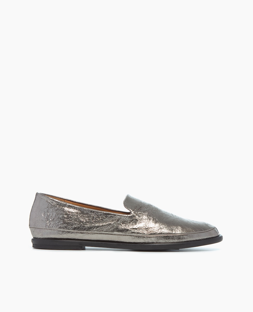 A metallic silver loafer with a sleek, low-profile design, featuring a slightly pointed toe, smooth texture, and a flat black sole.